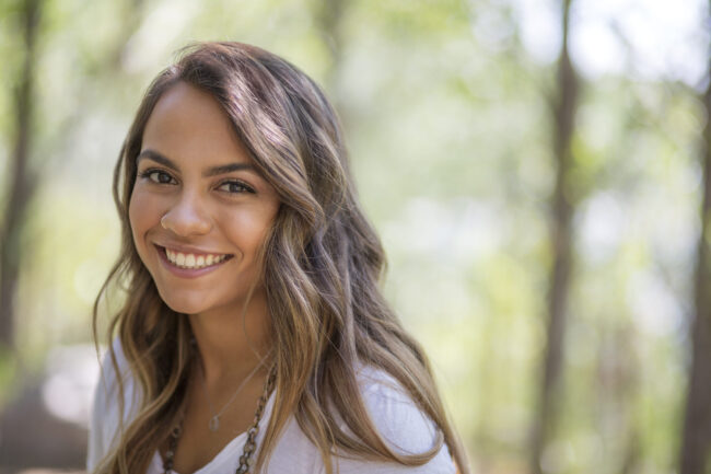 Head and shoulder portrait of pretty long haired teenage girl in woodland