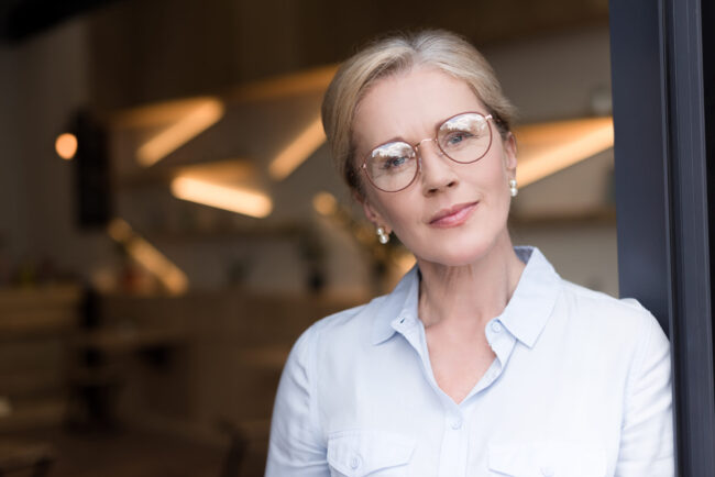 head and shoulders shot of pensive woman in eyeglasses looking at camera